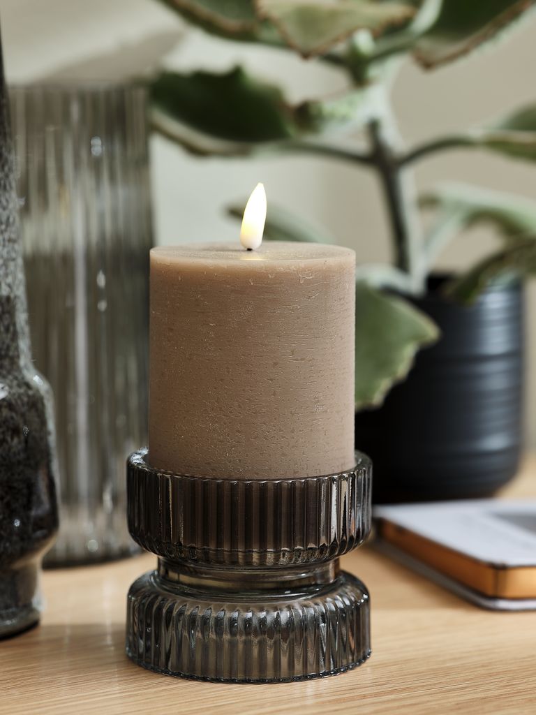Vela decorativa marrón en portavelas de cristal